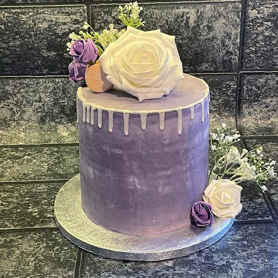 Purple wedding cake with white edible flower on it.